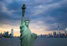 New York City Collects More as Tax Filers Leave Statue of Liberty with city skyline at dusk