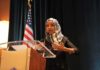 Clues Lead to Ilhan Omar’s Home – Search Warrant Ilhan Omar speaking at a podium with a microphone
