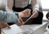 Hands of colleagues discussing a document during a meeting
