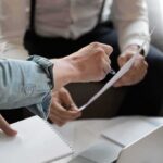 Hands of colleagues discussing a document during a meeting