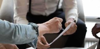 Hands of colleagues discussing a document during a meeting