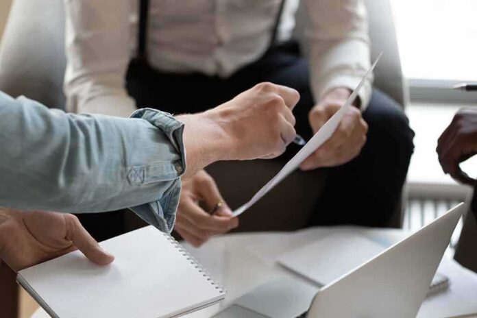 Hands of colleagues discussing a document during a meeting