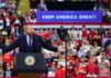 Judge’s Media Ruling Adds Twist to Trump Tour Crowd at a political rally with a speaker at a podium; Stephen Paea, Curtis Lofton, Walter Jones, John Sullivan, and Colin David Jones present