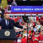 Judge’s Media Ruling Adds Twist to Trump Tour Crowd at a political rally with a speaker at a podium; Stephen Paea, Curtis Lofton, Walter Jones, John Sullivan, and Colin David Jones present