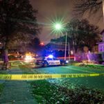Police car blocks residential street at night behind caution tape