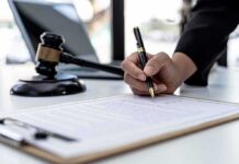 Judge Blocks Trump’s Firing of U.S. Attorney Hand signing legal document beside gavel and laptop