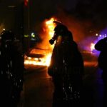 France Arrests Thousands as School Protests Escalate Riot police stand near burning cars at night