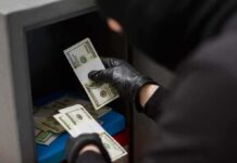 Old-Man Heist Twist Stuns Feds Gloved hands handling cash bundles inside a safe