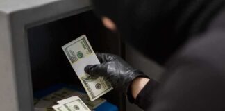 Gloved hands handling cash bundles inside a safe