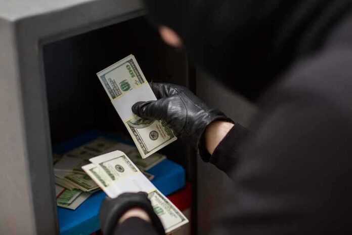 shutterstock_751847197 Gloved hands handling cash bundles inside a safe